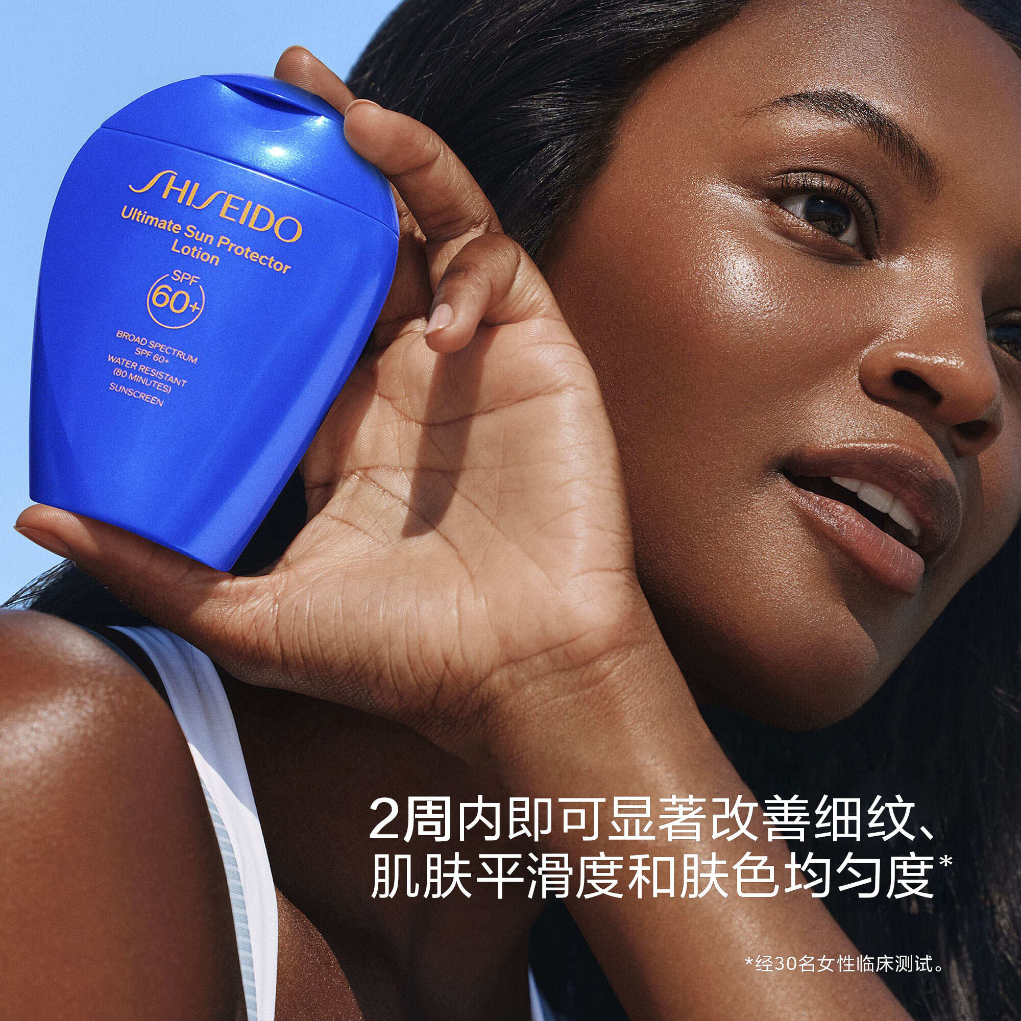 一位肤色光泽的女性将一瓶资生堂Ultimate Sun Protector Lotion SPF 60+贴近脸颊。叠加文字内容为：2周内即可显著改善细纹、肌肤平滑度和肤色均匀度。